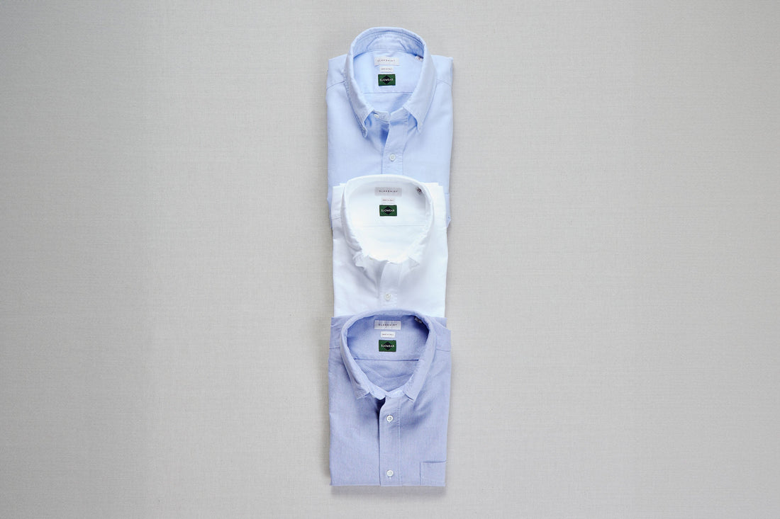 Three folded dress shirts arranged in a row on a neutral background.