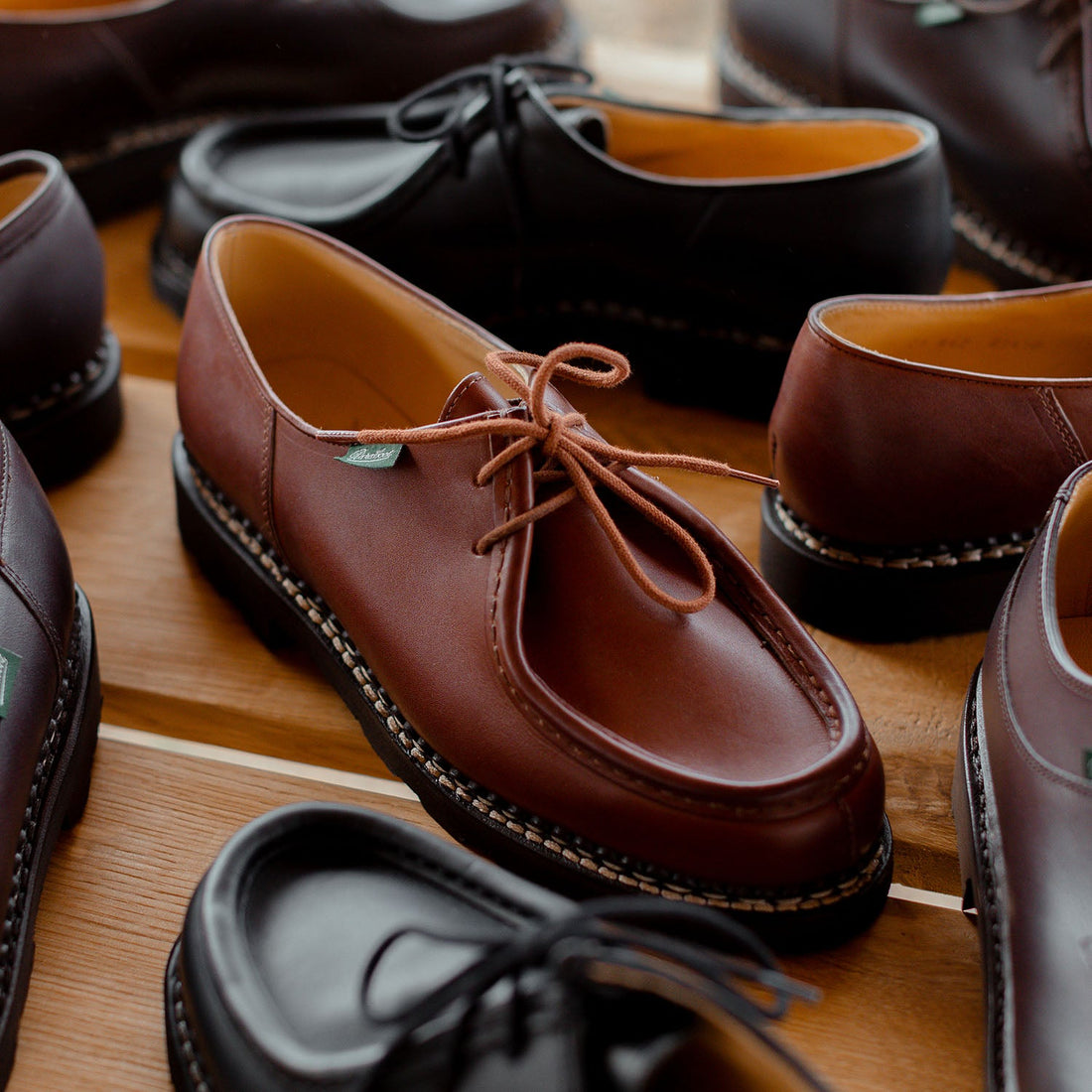 A variety of brown and black leather lace-up shoes displayed on a wooden surface.