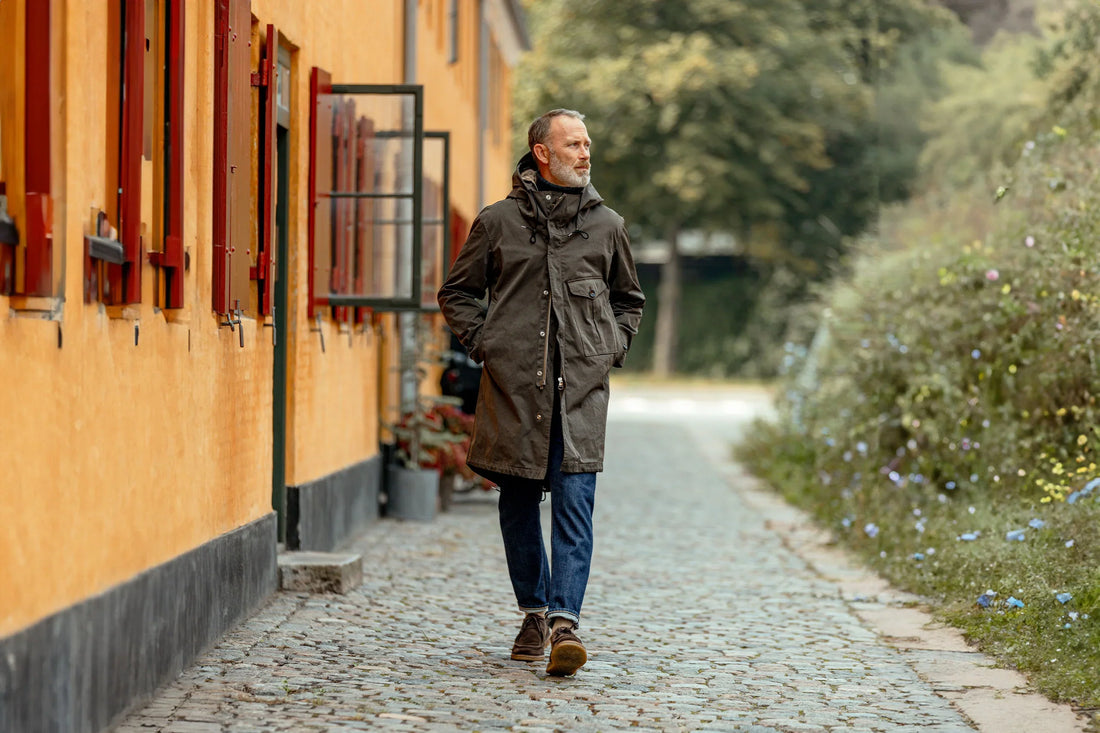 Man walking on a cobblestone path beside yellow buildings.