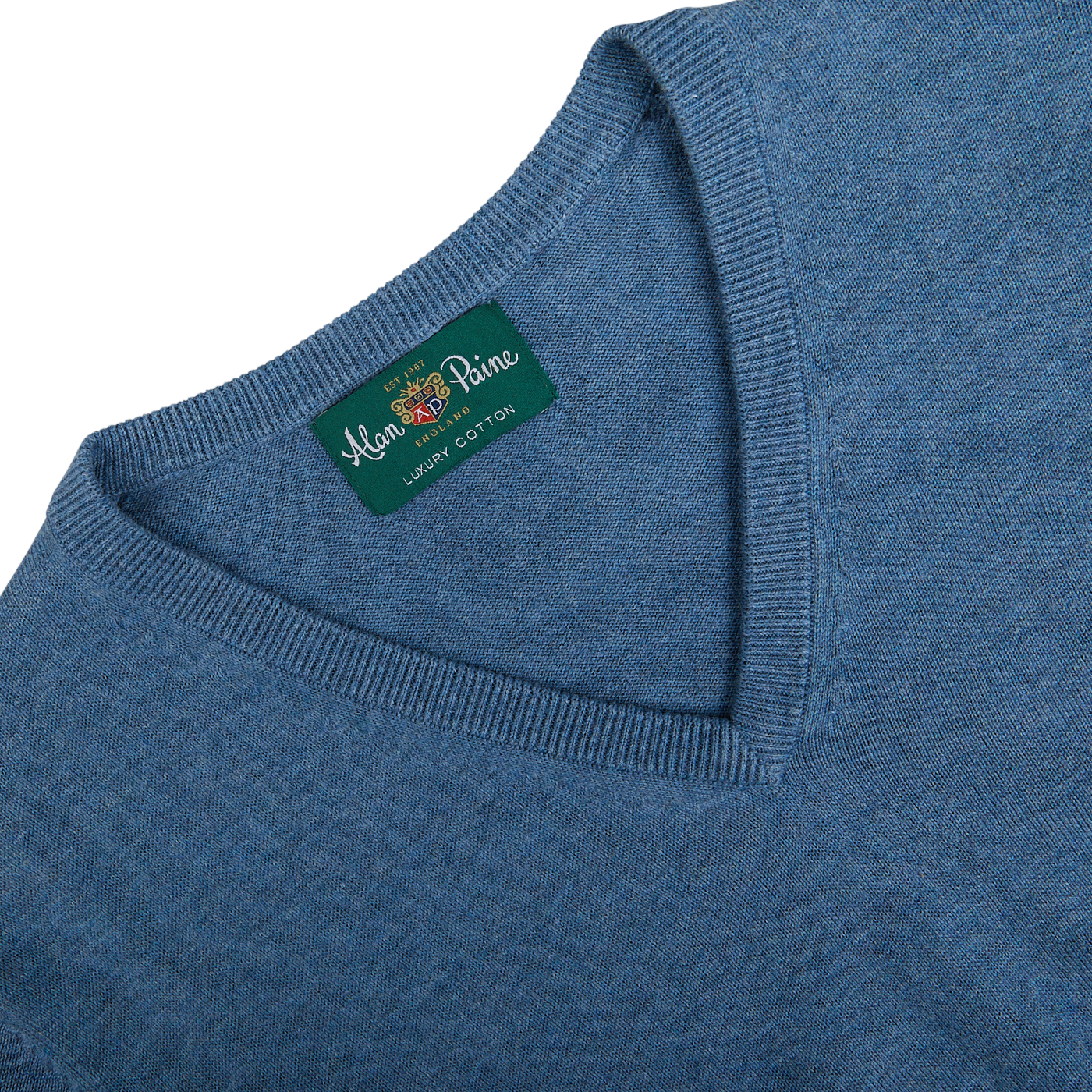 Close-up of a blue garment label reading "Alan Paine, 100% luxury cotton cashmere.
