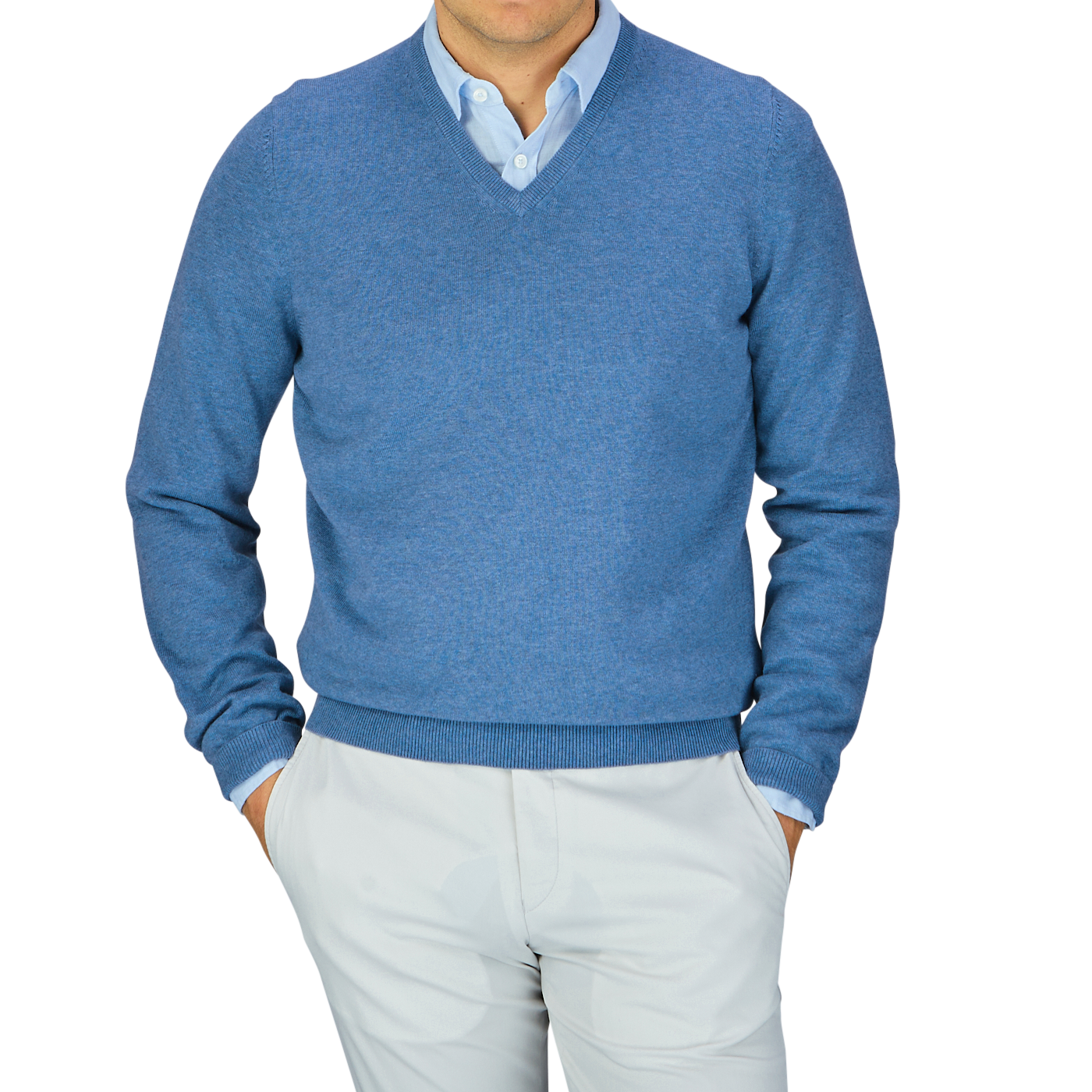 A person wearing an Airforce Blue Luxury Cotton V-Neck Sweater by Alan Paine over a light blue shirt, paired with white trousers, crafted from luxury cotton cashmere.