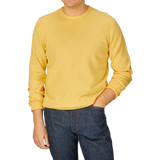 Man wearing a luxury cotton corn yellow Alan Paine crewneck sweater and blue jeans.