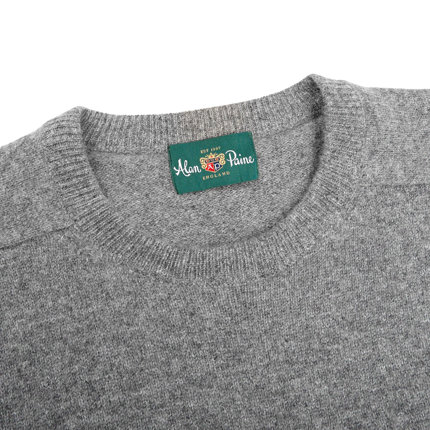 Close-up image of the Grey Melange Lambswool Crew Neck by Alan Paine, featuring a green label that reads "Alan Paine, England" sewn into the inside of the collar.