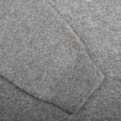 Close-up of a sleeve from the Alan Paine Grey Melange Lambswool Crew Neck with a visible stain near the cuff. The luxurious Australian lambswool fabric showcases a knit material that promises an updated fit and timeless appeal.