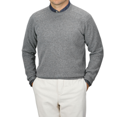 A person wearing an Alan Paine Grey Melange Lambswool Crew Neck over a blue collared shirt and beige pants, standing with hands in pockets against a plain background.