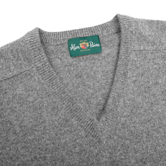 A close-up of a Grey Melange Lambswool V-Neck sweater by Alan Paine, crafted from luxurious Australian lambswool, with a green label showcasing the brand name.