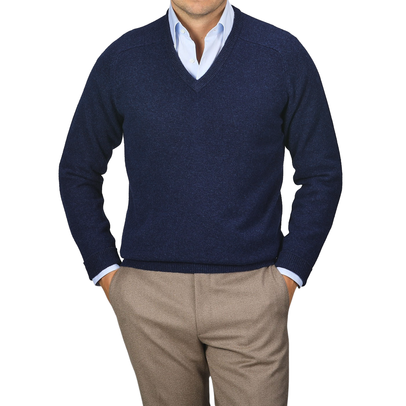 A person wearing an Alan Paine Indigo Blue Lambswool V-Neck sweater over a light blue dress shirt and beige pants, standing with hands in pockets against a plain background.