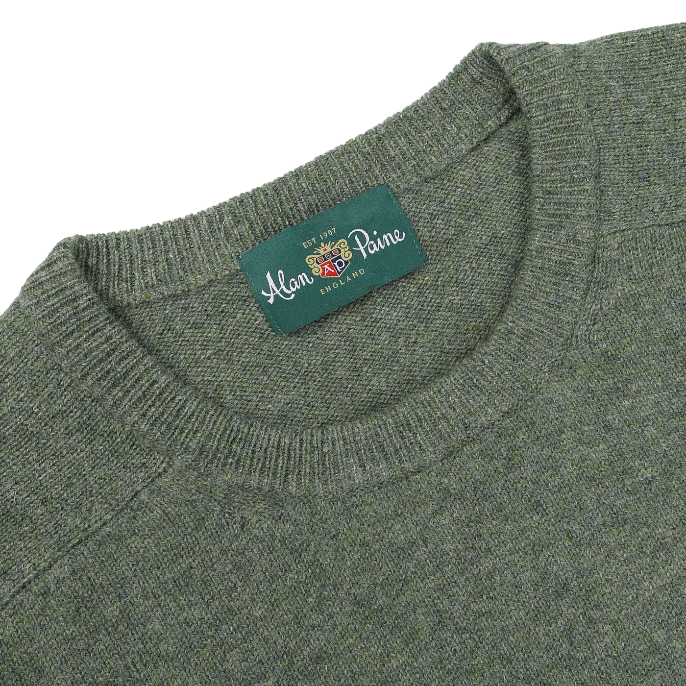 A close-up of the Landscape Green Lambswool Crew Neck sweater with a label that reads "Alan Paine, England," showcasing its contemporary fit made from luxurious Australian lambswool.