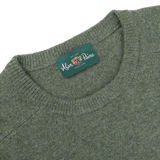 A close-up of the Landscape Green Lambswool Crew Neck sweater with a label that reads "Alan Paine, England," showcasing its contemporary fit made from luxurious Australian lambswool.