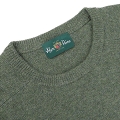 A close-up of the Landscape Green Lambswool Crew Neck sweater with a label that reads "Alan Paine, England," showcasing its contemporary fit made from luxurious Australian lambswool.