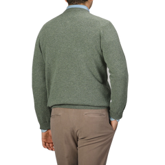 A person wearing an Alan Paine Landscape Green Lambswool V-Neck sweater and beige pants is shown from behind against a plain background.