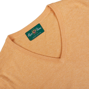 Close-up of an Alan Paine Mango Orange Luxury Cotton V-Neck Sweater with a branded label inside the collar.