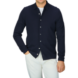 A man wearing a navy blue Alan Paine Luxury Cotton Knitted Overshirt and white pants.