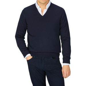 Man wearing a Navy Blue Luxury Cotton V-Neck Sweater by Alan Paine over a white shirt with dark trousers against a grey background.