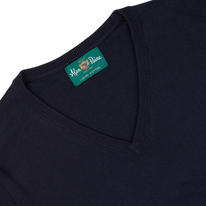 Close-up of a dark blue, Alan Paine luxury cotton cashmere summer v-neck sweater neckline featuring an Alan Paine brand label.