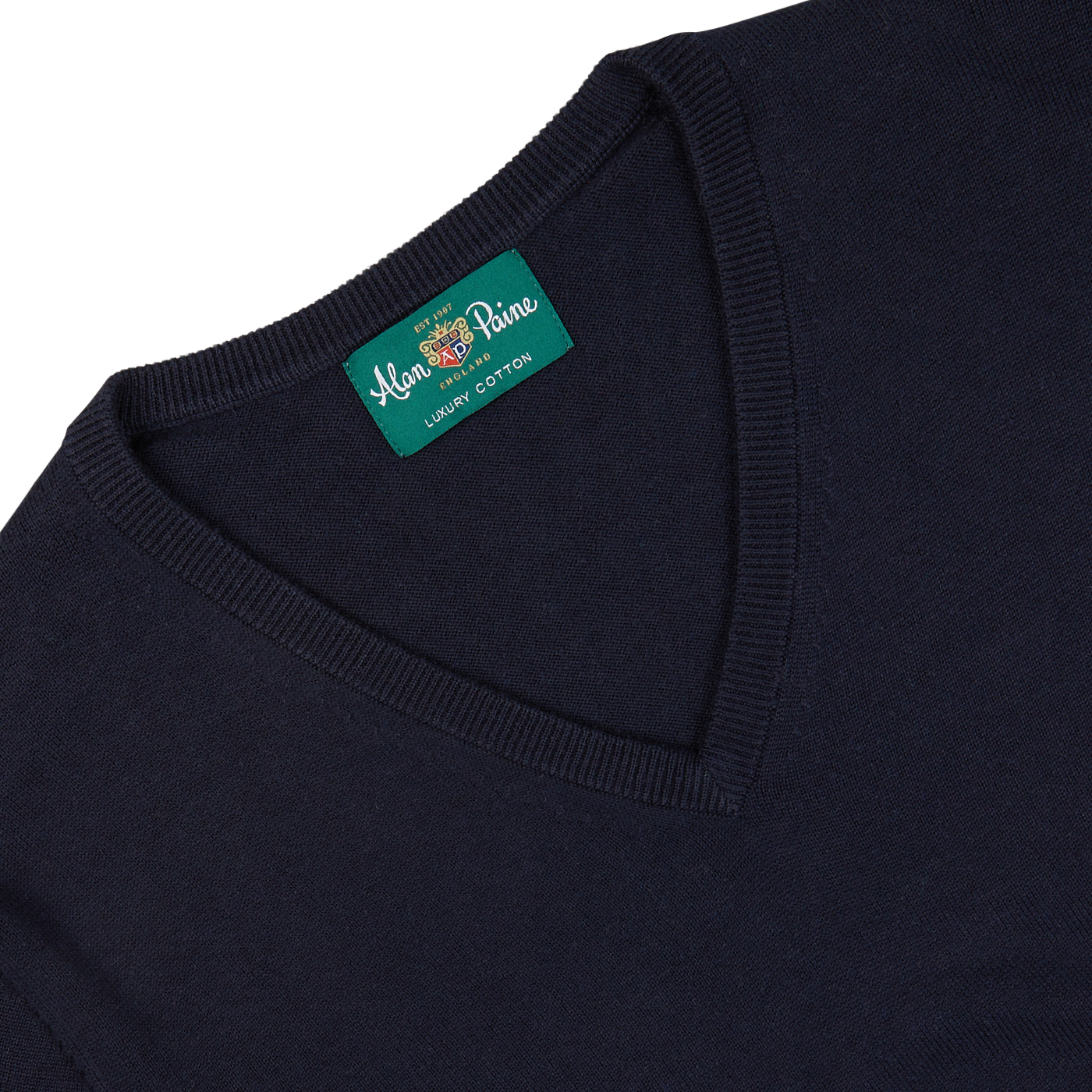 Close-up of a dark blue, Alan Paine luxury cotton cashmere summer v-neck sweater neckline featuring an Alan Paine brand label.