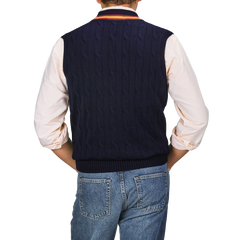 A person wearing an Alan Paine Navy Blue Striped Merino Wool Cricket Slipover over a white shirt with rolled-up sleeves and blue jeans, seen from the back.