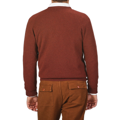 Back view of a person wearing an Alan Paine Nebula Red Brown Lambswool V-Neck and brown pants, standing against a plain background.