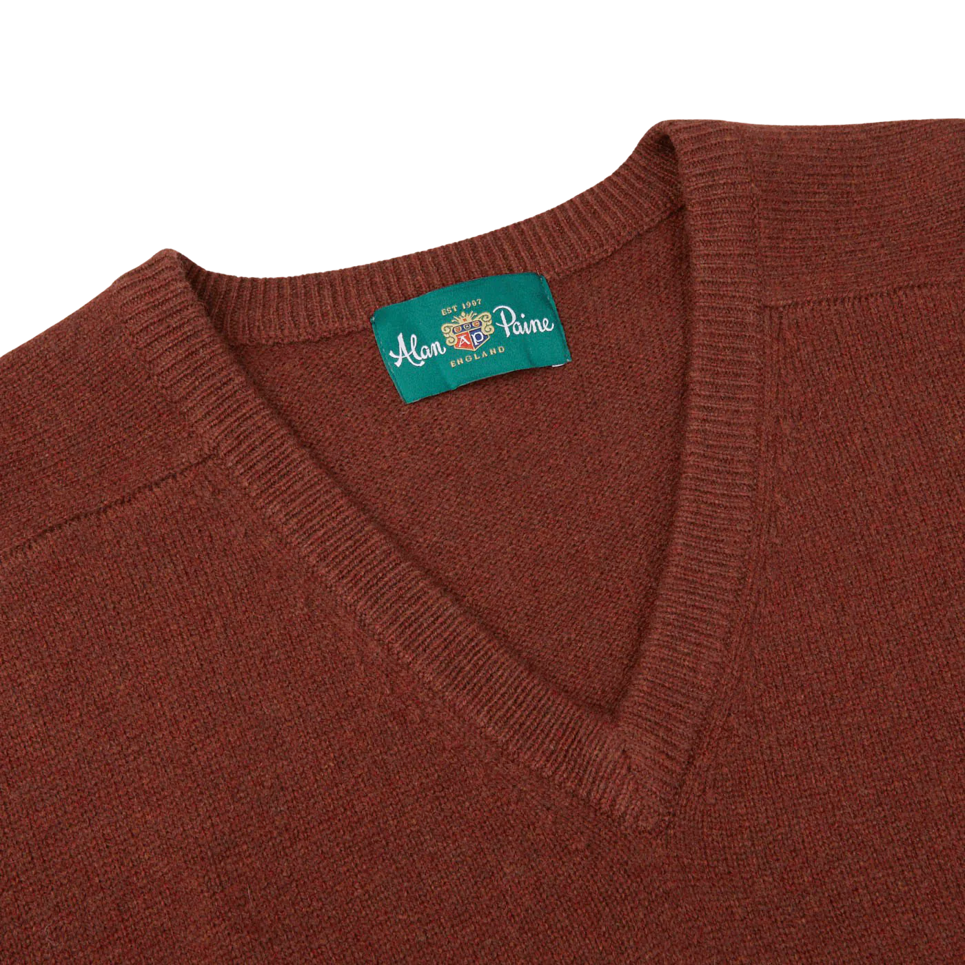 Introducing the Nebula Red Brown Lambswool V-Neck by Alan Paine, a soft Australian lambswool knit sweater featuring a V-neck design and adorned with a green label displaying the brand name at the neckline.