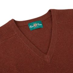 Introducing the Nebula Red Brown Lambswool V-Neck by Alan Paine, a soft Australian lambswool knit sweater featuring a V-neck design and adorned with a green label displaying the brand name at the neckline.