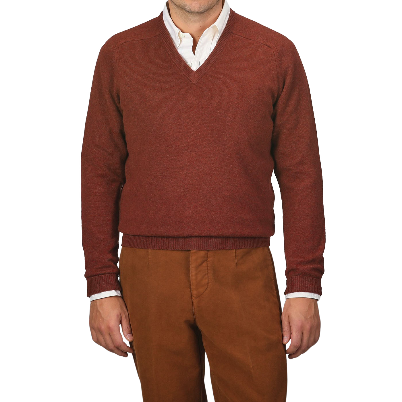 A person wearing an Alan Paine Nebula Red Brown Lambswool V-Neck sweater over a white button-down shirt, paired with brown pants. The background is plain gray.