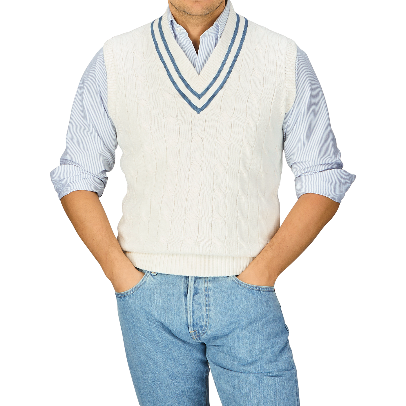 Man wearing a white Alan Paine Off-White Blue Striped Cotton Cricket Slipover over a blue-striped shirt with hands on hips.