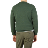The contemporary version of a man wearing an Alan Paine Rosemary Green Lambswool crew neck sweater and khaki pants.