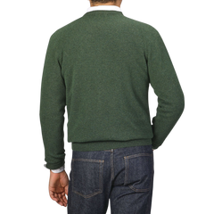 A person wearing an Alan Paine Rosemary Green Lambswool Crew Neck sweater and blue jeans, seen from the back.