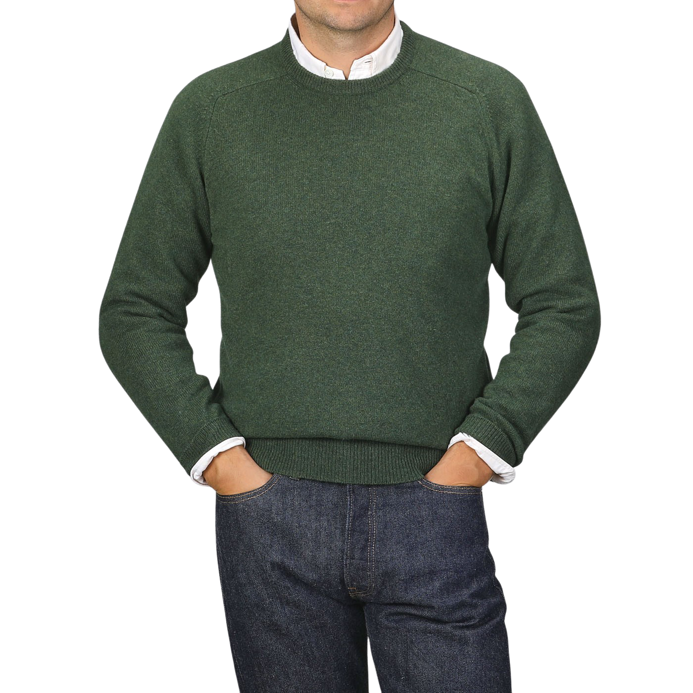 A person wearing an Alan Paine Rosemary Green Lambswool Crew Neck over a white shirt with blue jeans, standing with their hands in their pockets against a plain background.