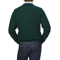 A person wearing an Alan Paine Tartan Green Lambswool V-Neck and blue jeans, standing with their back to the camera.