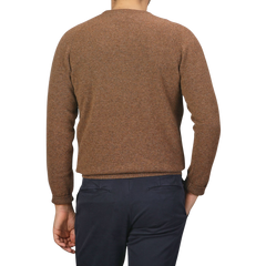 A person wearing an Alan Paine Tobacco Brown Lambswool Crew Neck with saddle shoulder detailing and navy blue pants is seen from the back against a plain white background.