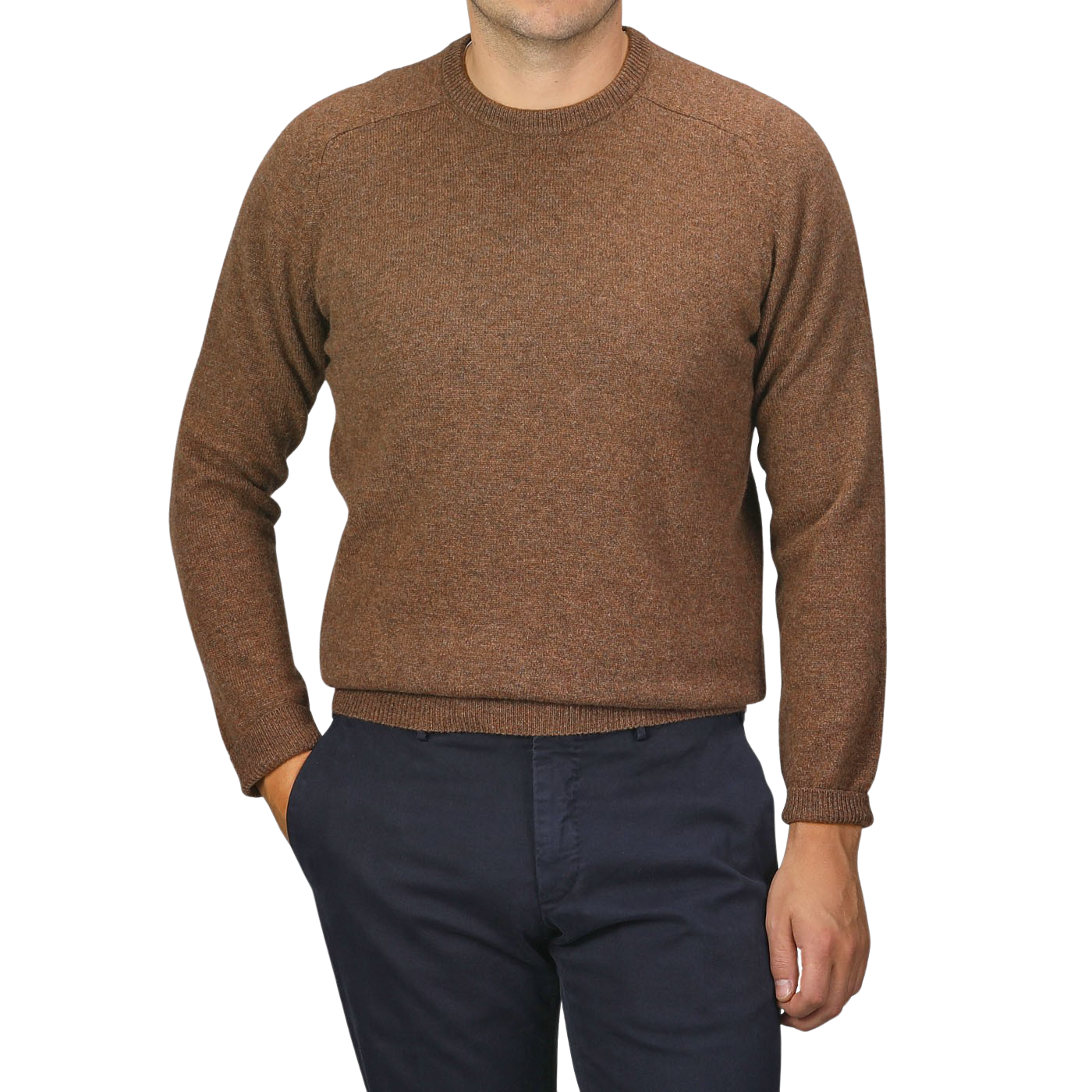 A person wearing an Alan Paine Tobacco Brown Lambswool Crew Neck and dark blue pants, with their left hand in their pocket.