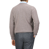 A person wearing an Alan Paine Vole Beige Lambswool V-Neck sweater and dark gray pants is shown from the back against a plain background.