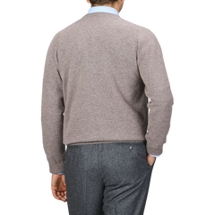 A person wearing an Alan Paine Vole Beige Lambswool V-Neck sweater and dark gray pants is shown from the back against a plain background.