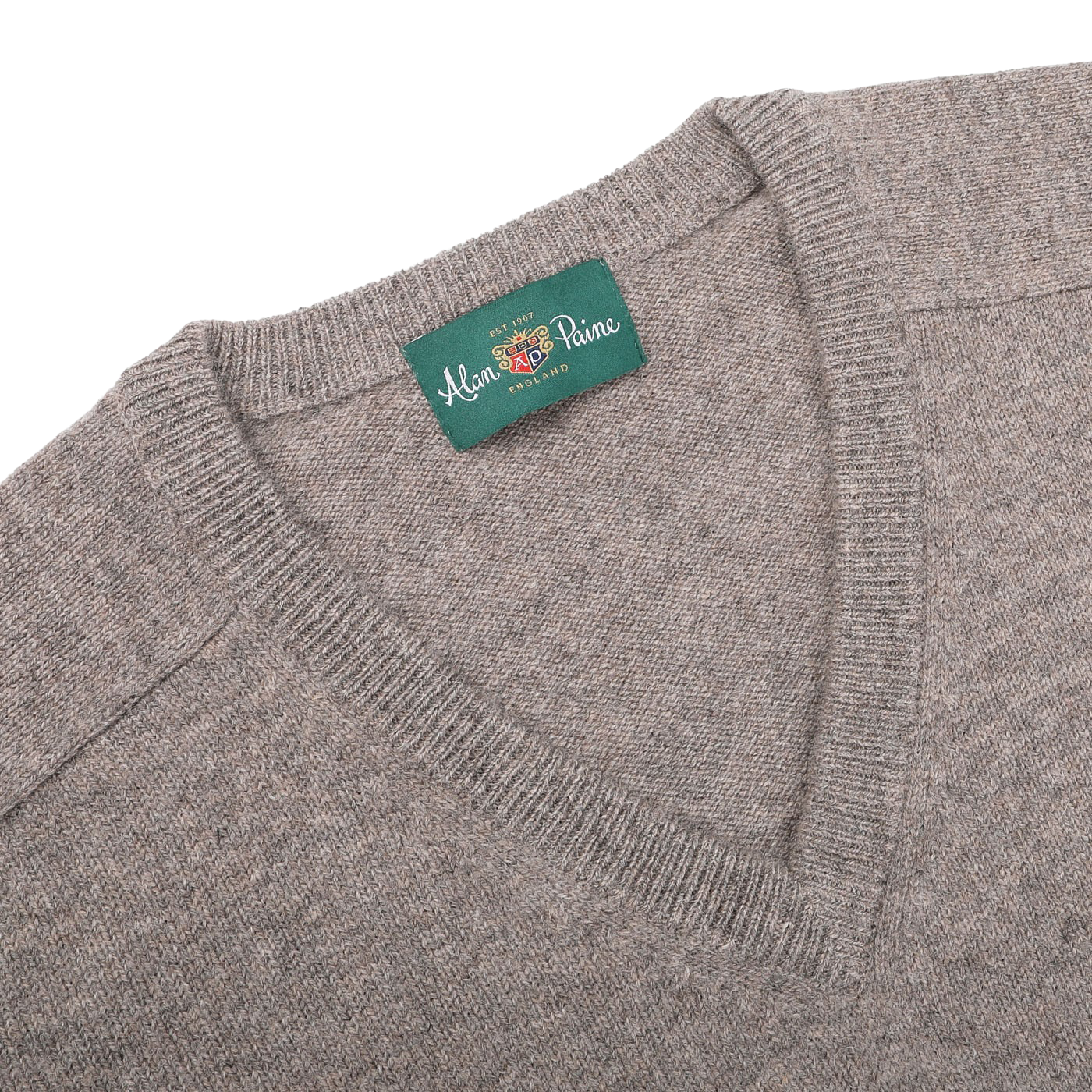 The Vole Beige Lambswool V-Neck, crafted from Australian lambswool, features an updated fit and a green label that reads "Alan Paine" and "EST 1907.