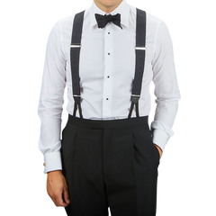 A person stands wearing a white dress shirt, black bow tie, and Black James Bond Moiré 38 mm Braces by Albert Thurston, with hands in black dress pants pockets against a plain background.