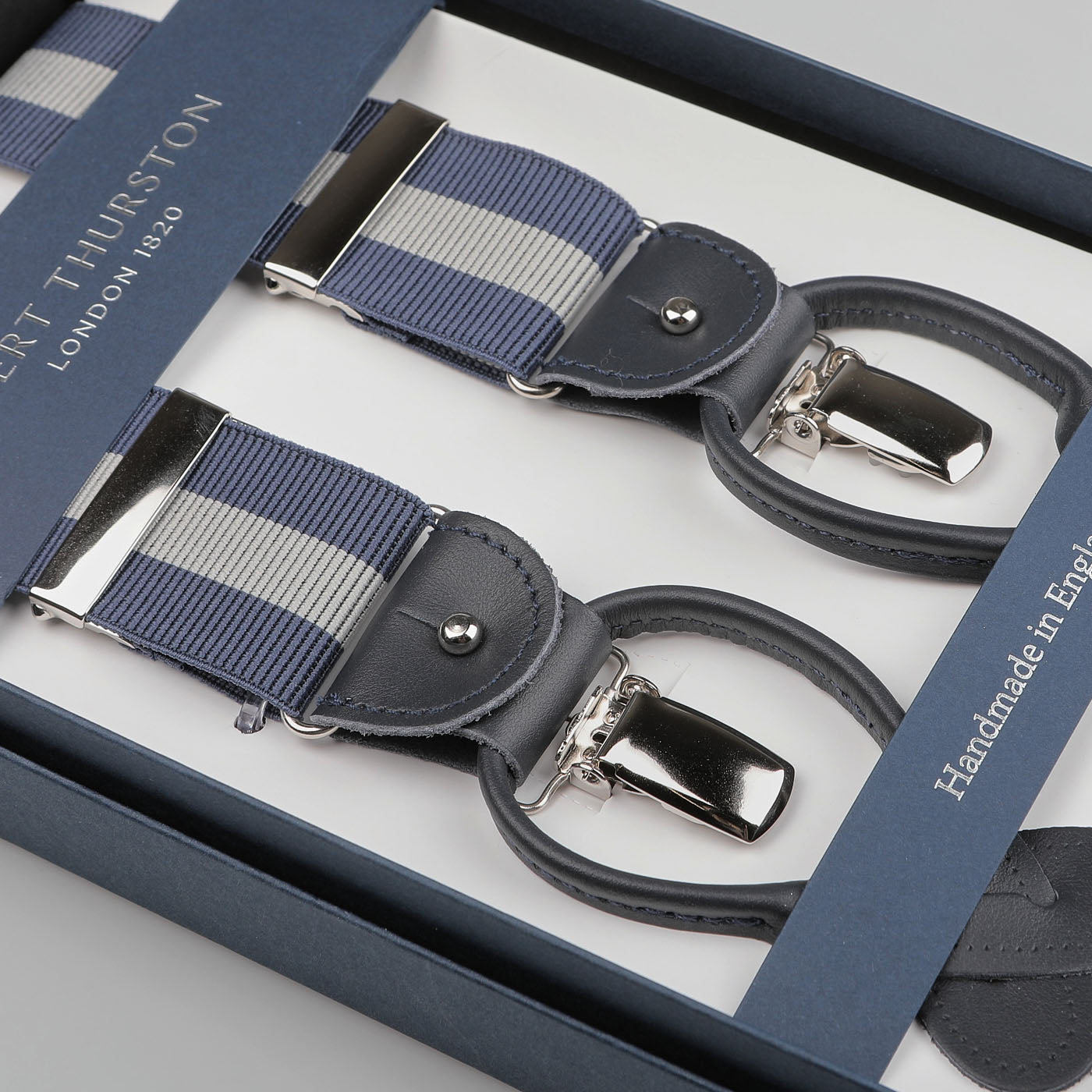 A pair of Blue Grey Striped Nylon 35 mm Braces by Albert Thurston, featuring leather details and metal clips, elegantly presented in a box labeled "Albert Thurston London 1820.