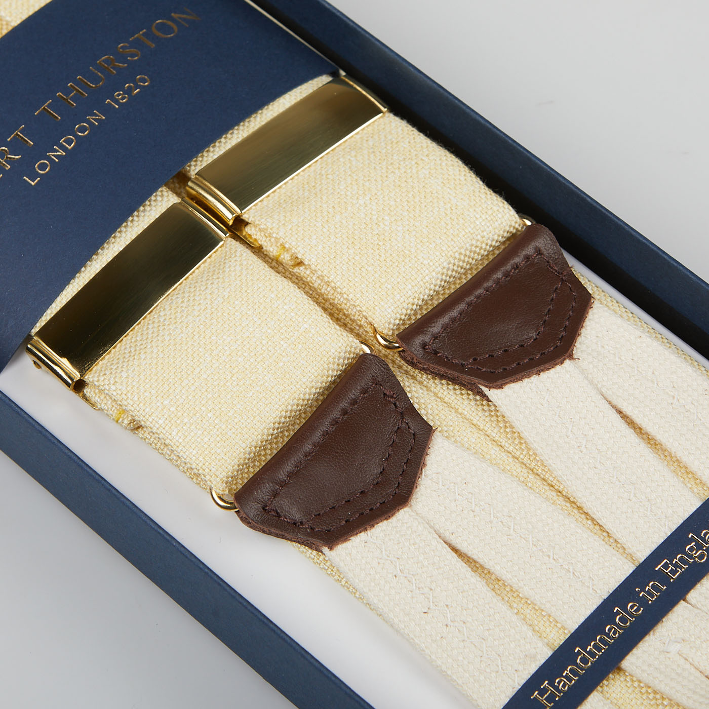 A boxed set of Cream Hemp Leather 35 mm Braces crafted from cream pure hemp, featuring brown leather accents and gold hardware. Labeled "Albert Thurston," the text at the bottom proudly reads "Handmade in England.