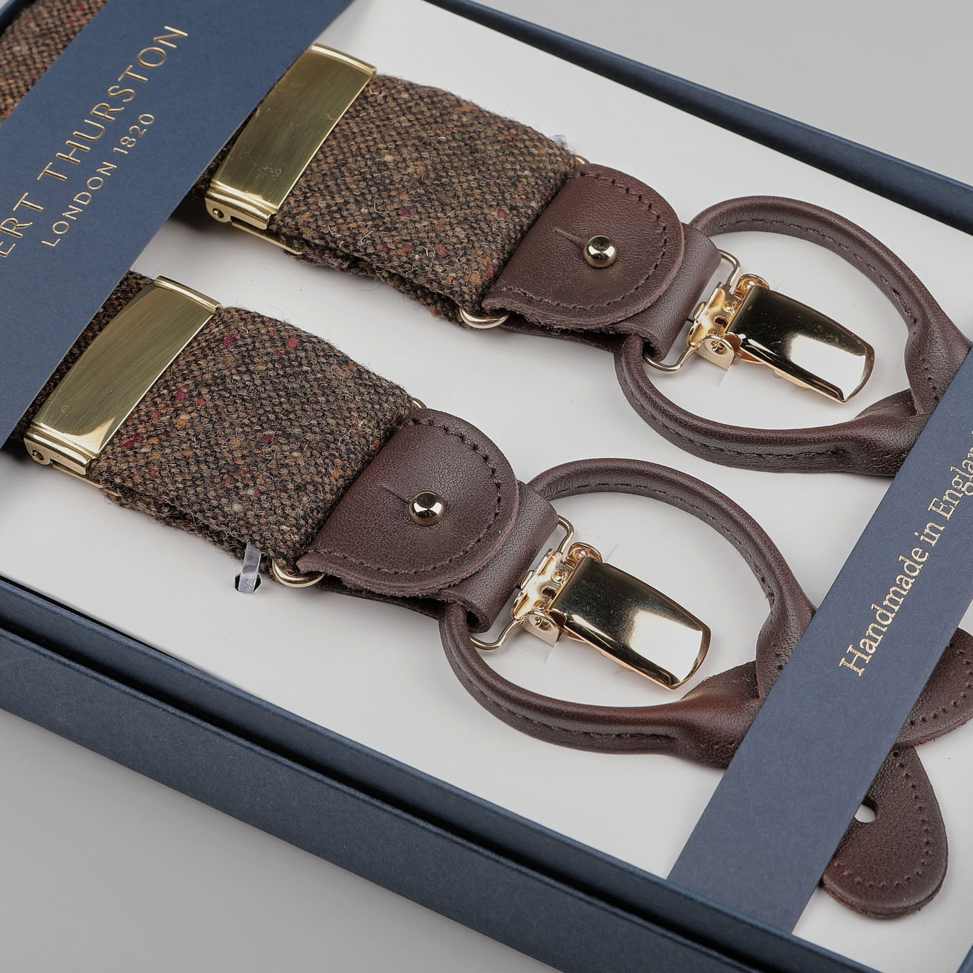 A boxed pair of Albert Thurston Dark Brown Donegal Tweed 35mm braces with leather straps and gold-toned clips, labeled as handmade in England.