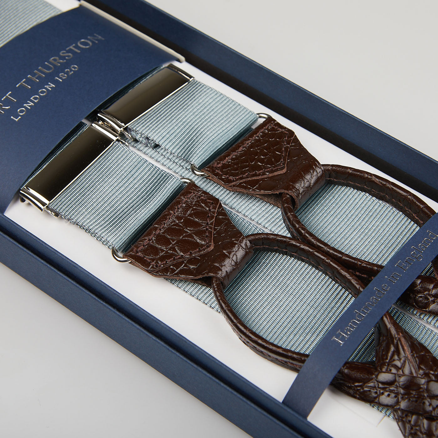 A pair of Dove Grey James Bond Nylon 35mm Braces, displayed in an open blue gift box with a navy lining featuring the British brand "Albert Thurston.