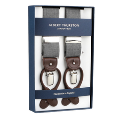 Box of "Light Grey Wool Fresco 35mm Braces" features gray fabric with brown leather details and metal clips. Labeled "Albert Thurston," it proudly states "Handmade in England," showcasing meticulous craftsmanship.