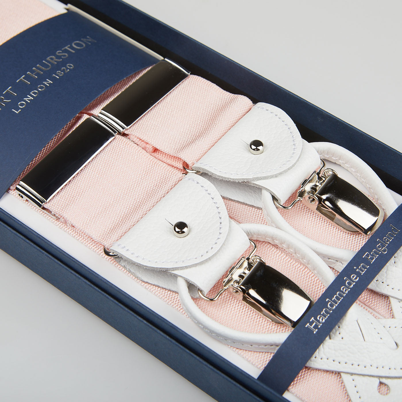 Pink and white handmade Light Pink Nylon White Leather 40 mm braces with silver clips and leather details, presented in an open blue box with the brand name "Albert Thurston London 1893" visible.