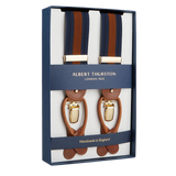 A boxed set of Albert Thurston Navy Brown Striped Nylon Leather 35 mm Braces with brown leather detailing and blue and brown fabric straps. The packaging, indicative of this esteemed British brand, proudly notes these suspenders are handmade in England.