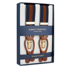 A boxed set of Albert Thurston Navy Brown Striped Nylon Leather 35 mm Braces with brown leather detailing and blue and brown fabric straps. The packaging, indicative of this esteemed British brand, proudly notes these suspenders are handmade in England.