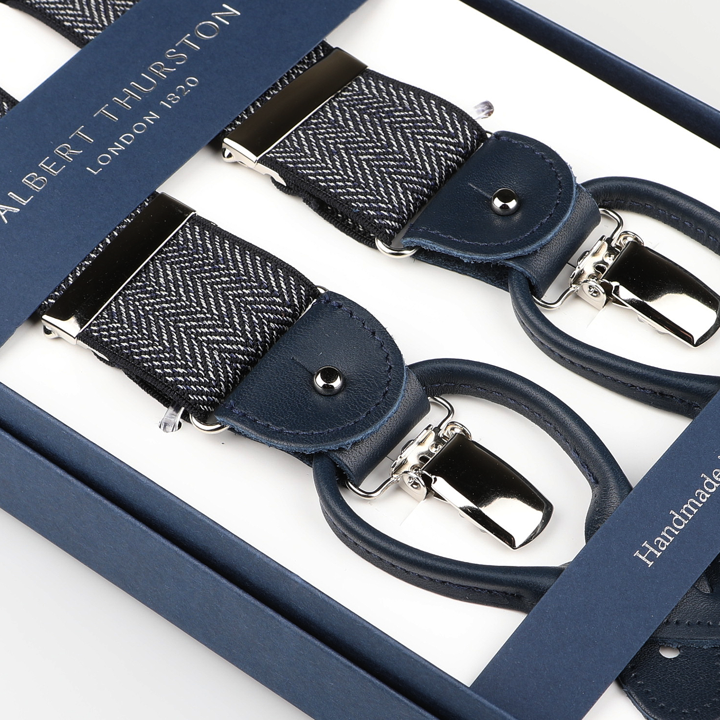 Close-up of Albert Thurston Navy Blue Herringbone Nylon Elastic 38mm Braces in a box, featuring leather details and metallic clasps for classic elegance.