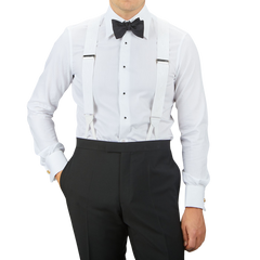 A man wearing a white dress shirt with black buttons, a black bow tie, black trousers, and White James Bond Moiré 38 mm Braces by Albert Thurston—a classic James Bond accessory.