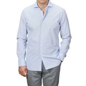 A person stands with one hand in their pocket, wearing an Alessandro Gherardi Blue Gingham Checked Cotton Single Cuff Shirt paired with gray trousers.