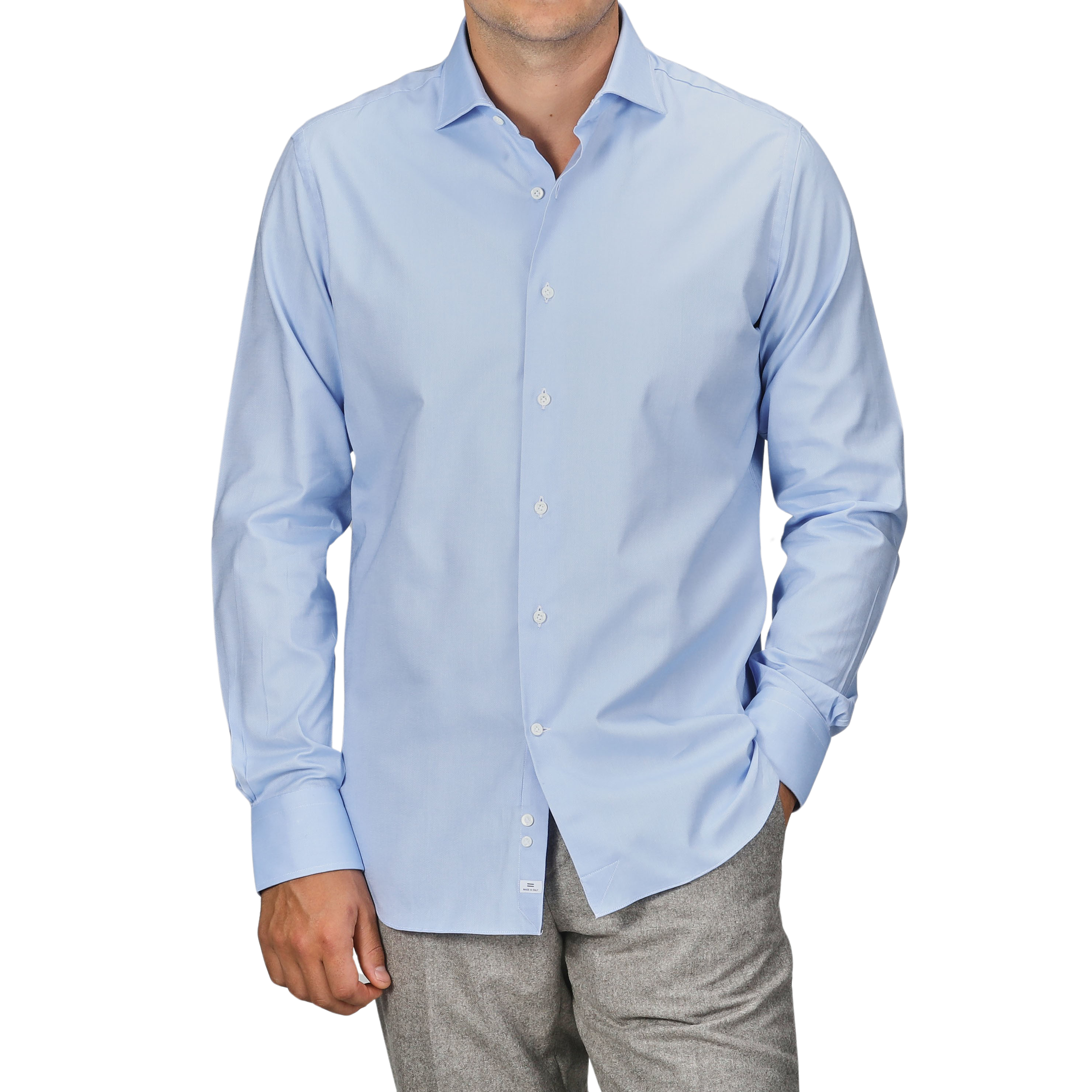 A person dressed in an Alessandro Gherardi Light Blue Cotton Oxford Single Cuff Shirt, with the sleeves down, and grey pants, standing with one hand in their pocket. The head is not visible.