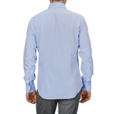 A person wearing a light blue Sky Blue Cotton Twill Single Cuff Shirt by Alessandro Gherardi and gray pants, viewed from the back.