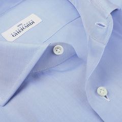 Close-up of a folded sky blue formal shirt with a fabric tag reading "Alessandro Gherardi" near the collar and a partially open button-down front, showcasing the quality of pure cotton in men's shirts.